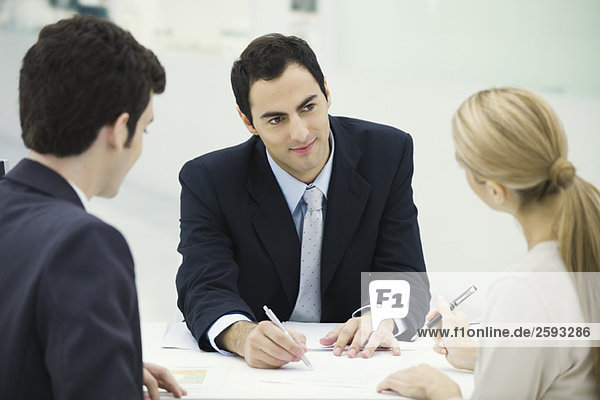 Meeting between professional and clients  woman preparing to sign document