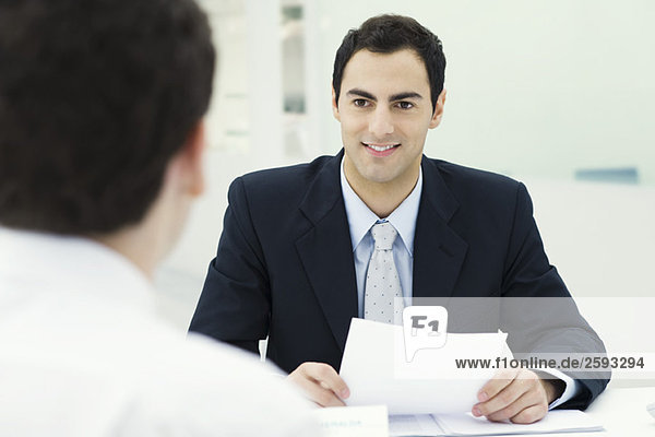 Geschäftsmann hält Dokument  lächelnd auf Client