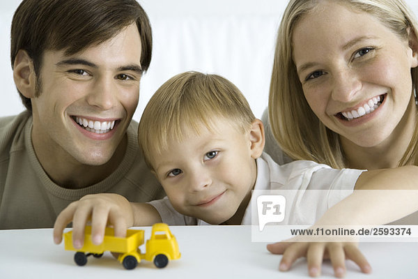 Familie lächelt in die Kamera  Junge spielt mit Spielzeugwagen