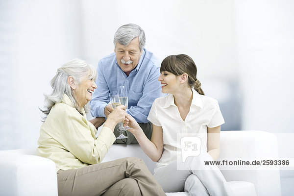 Senior Eltern und erwachsene Tochter klirren Champagnergläser  lächelnd