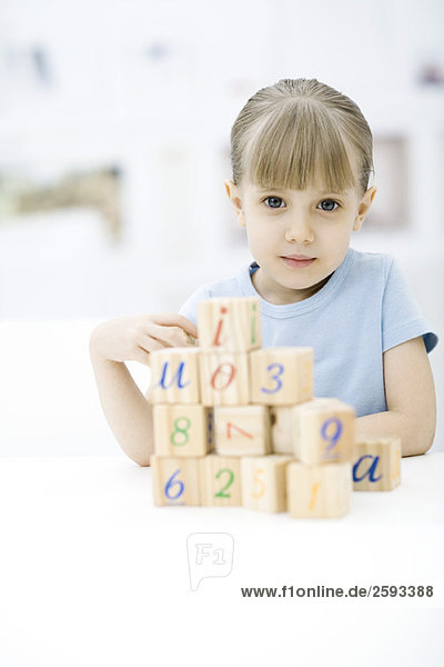 Little girl stacking blocks  looking at camera  portrait
