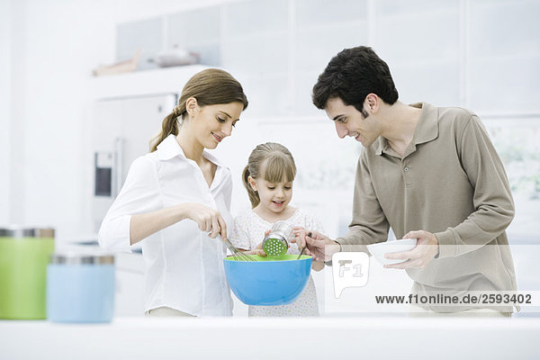 Kleines Mädchen hilft Eltern beim Kochen in der Küche