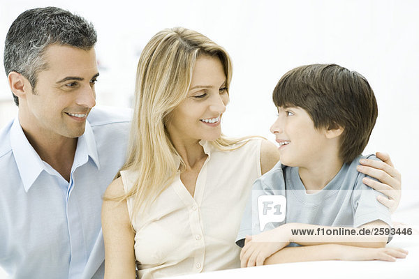 Family sitting together  smiling  mother's arm around son's shoulder