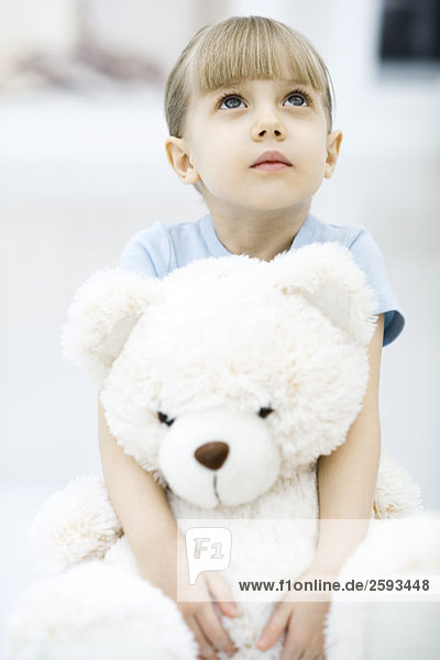 Little girl holding teddy bear  looking up