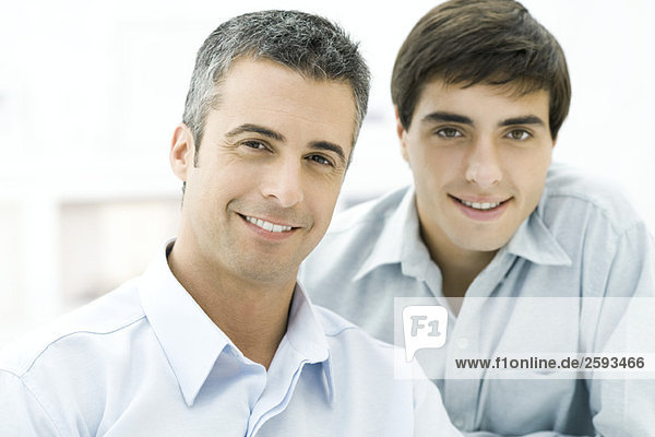Father and adult son smiling at camera  portrait
