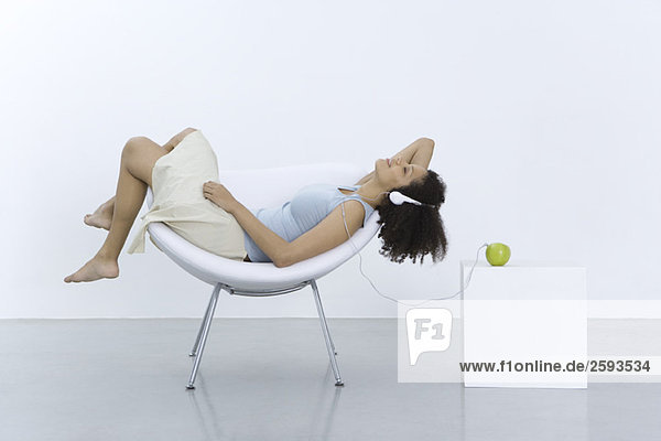 Frau im Sessel liegend  Kopfhörer an Apfel angeschlossen  Seitenansicht