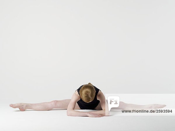 Eine junge Frau  die die'Spread Leg Forward Fold' Yogastellung praktiziert.