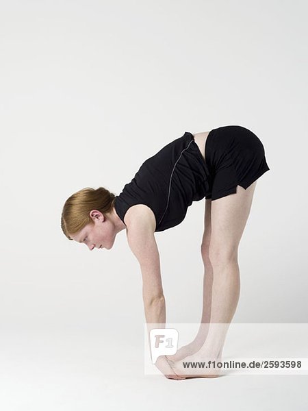 Eine junge Frau  die die'Upward Forward Fold' Yogastellung praktiziert.