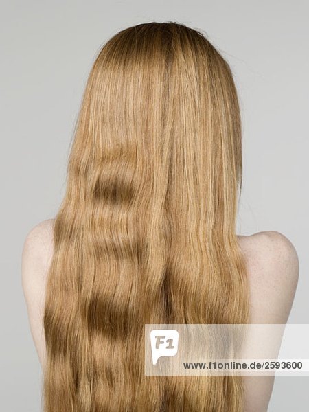 Eine junge nackte Frau mit langen Haaren  Rückansicht