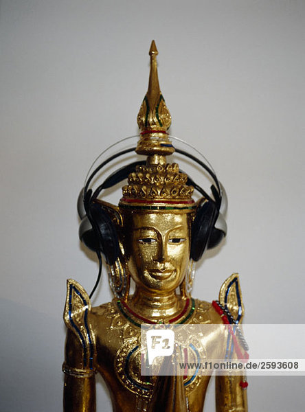Eine betende goldene Buddha-Statue mit Kopfhörer an