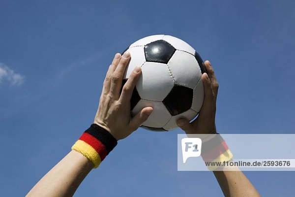 Hände halten einen Fußball in der Luft