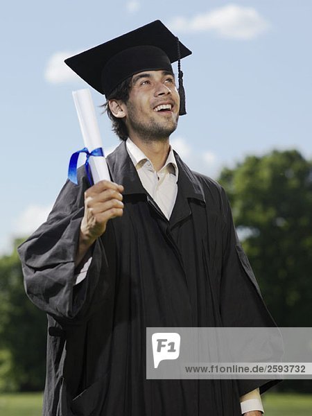 A male graduate holding a diploma