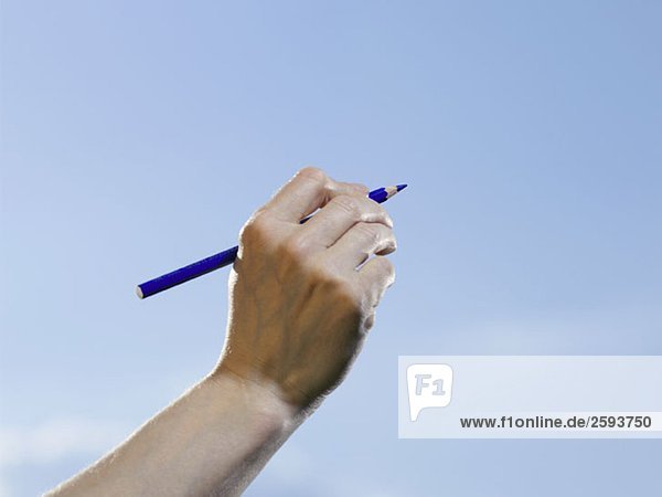 Eine menschliche Hand  die einen blauen Bleistift hält.