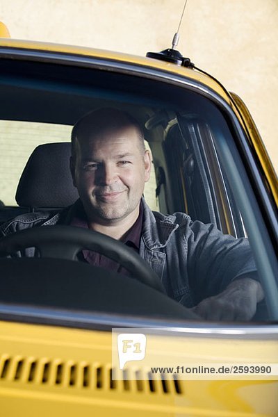 Ein Taxifahrer sitzt in seinem Auto und lächelt.