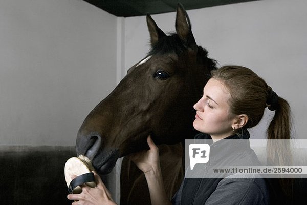 Eine junge Frau  die ein Pferd pflegt.