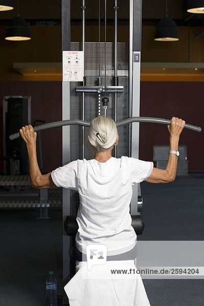 Eine ältere Frau  die eine seitliche Ausziehgewichtsmaschine benutzt.