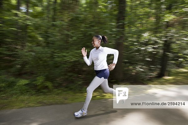 A woman jogging through a wooded park