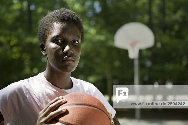 Eine junge  ernsthafte Frau mit einem Basketball.