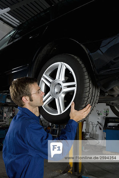 Ein Mechaniker  der das Rad eines Autos in einer Reparaturwerkstatt befestigt.