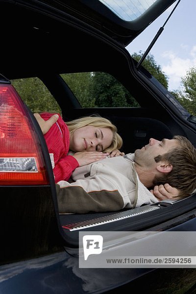 Ein Paar schläft auf dem Rücksitz eines Autos.