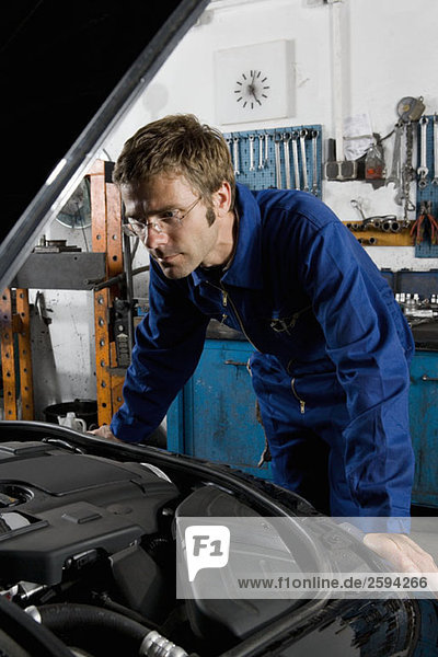 A car mechanic examining a car engine