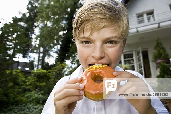 Ein kleiner Junge  der einen Donut isst.
