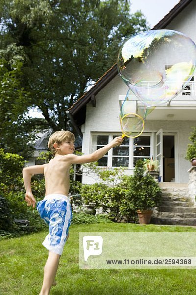 Ein Junge macht eine Blase mit einem Blasenstab.