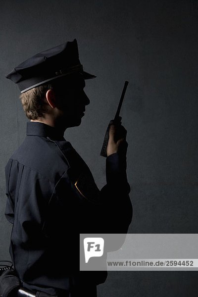 Ein Polizist  der ein Funkgerät benutzt.