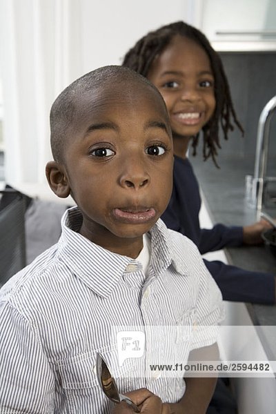 A young boy making a funny face while his brother smiles behind him