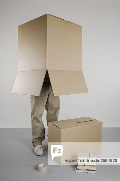 Eine Person  die mit einer Kiste über dem Kopf steht.