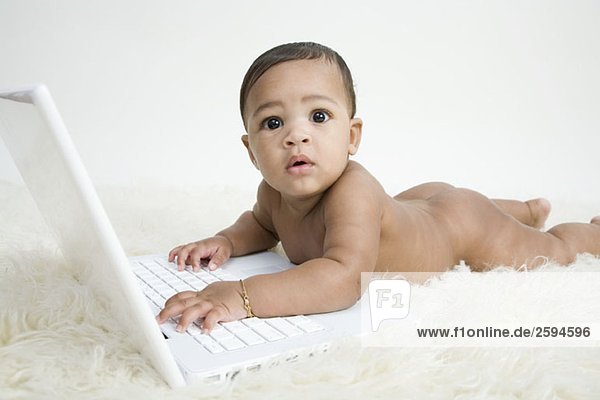 Ein Baby mit einem Laptop  vorne liegend