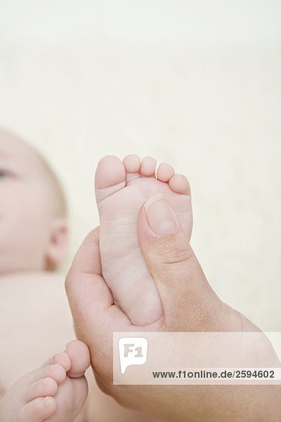 Eine menschliche Hand  die den Fuß eines Babys hält.