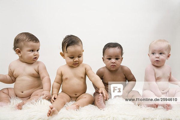Vier Babys sitzend in einer Reihe