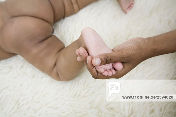 Eine menschliche Hand  die den Fuß eines Babys hält.