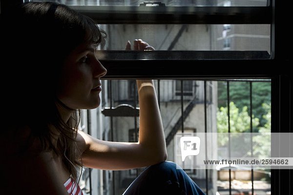 Eine lateinamerikanische Frau sitzt auf einem Fensterbrett.