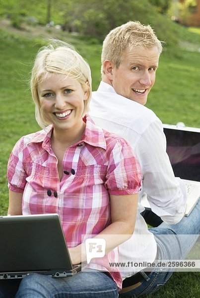 Blondes Mädchen und Kerl im Park mit Computern