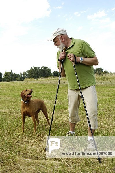 Mature man looking at dog in field