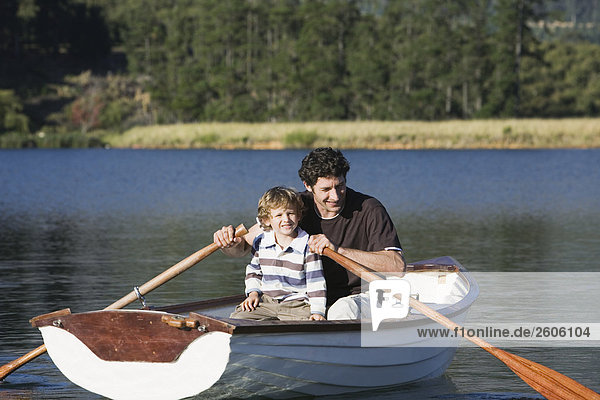 Father and son (4-7) rowing in rowing boat on lake