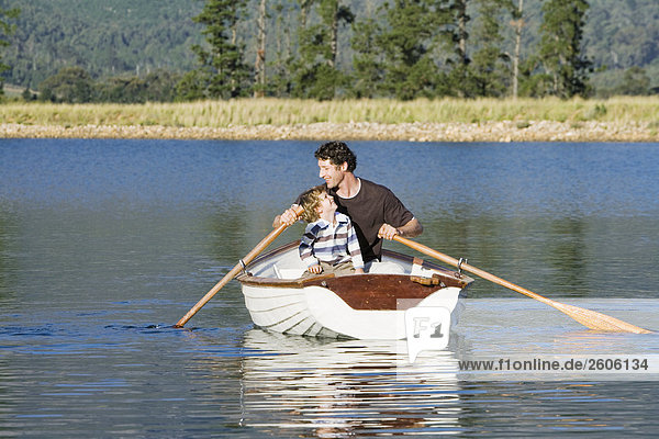 Father and son (4-7) rowing in rowing boat on lake