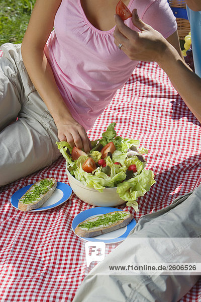 Junges Paar im Park beim Picknick mit Salat und Schnittlauchbrot Nahaufnahme