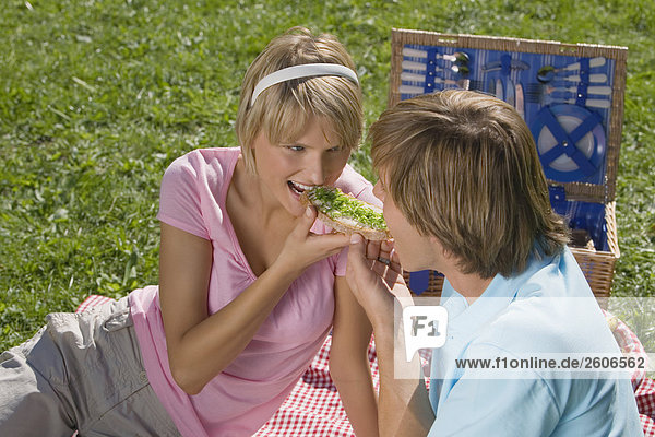Junges Paar im Park beim Picknick essen gemeinsam Schnittlauchbrot