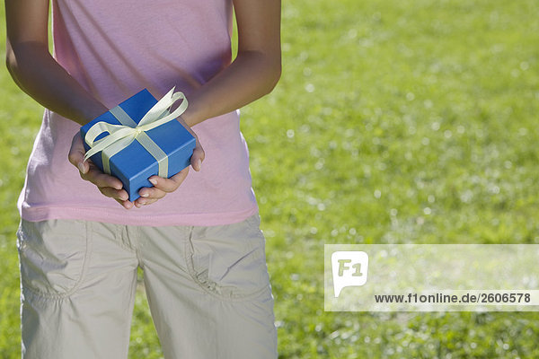 Frau steht in der Wiese mit Geschenk in der Hand Nahaufnahme