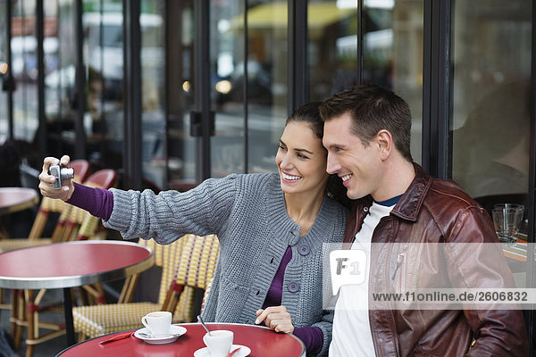 Junges Paar sitzt draußen im Straßencafe fotografiert sich Paris Frankreich