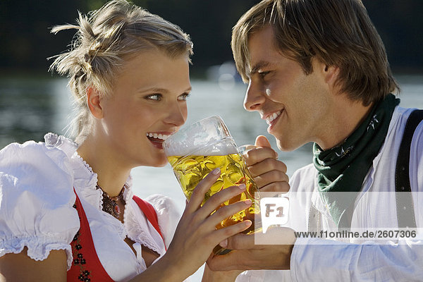 Junges Paar in Tracht teilen sich eine Mass Bier Biergarten am Seehaus Englischer Garten Nahaufnahme