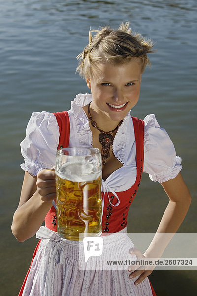 Junge Frau in Tracht steht mit Mass Bier in der Hand im Biergarten am Seehaus Englischer Garten Nahaufnahme