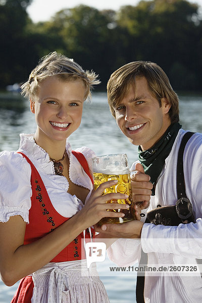 Junges Paar in Tracht halten gemeinsam eine Mass Bier Biergarten am Seehaus Englischer Garten