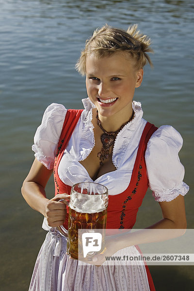 Junge Frau in Tracht steht mit Mass Bier in der Hand im Biergarten am Seehaus Englischer Garten Nahaufnahme