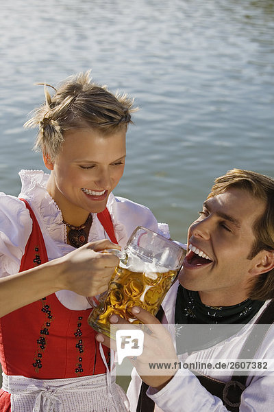 Junges Paar in Tracht teilen sich eine Mass Bier Mann trinkt Biergarten am Seehaus Englischer Garten Nahaufnahme