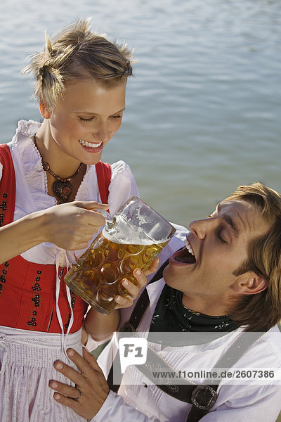 Junges Paar in Tracht teilen sich eine Mass Bier Frau gibt Mann zu trinken Biergarten am Seehaus Englischer Garten Nahaufnahme