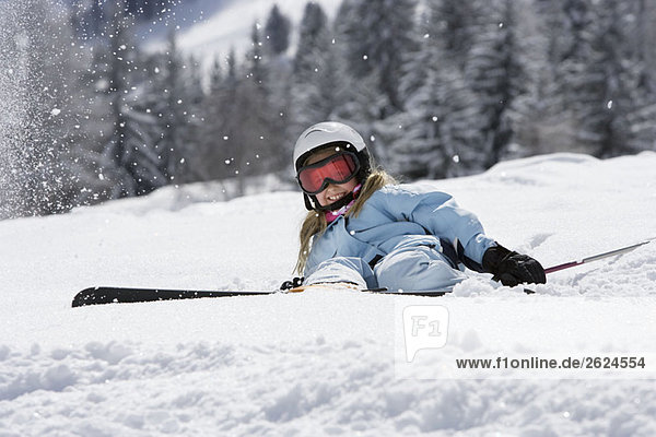 Girl with skis lying on snow